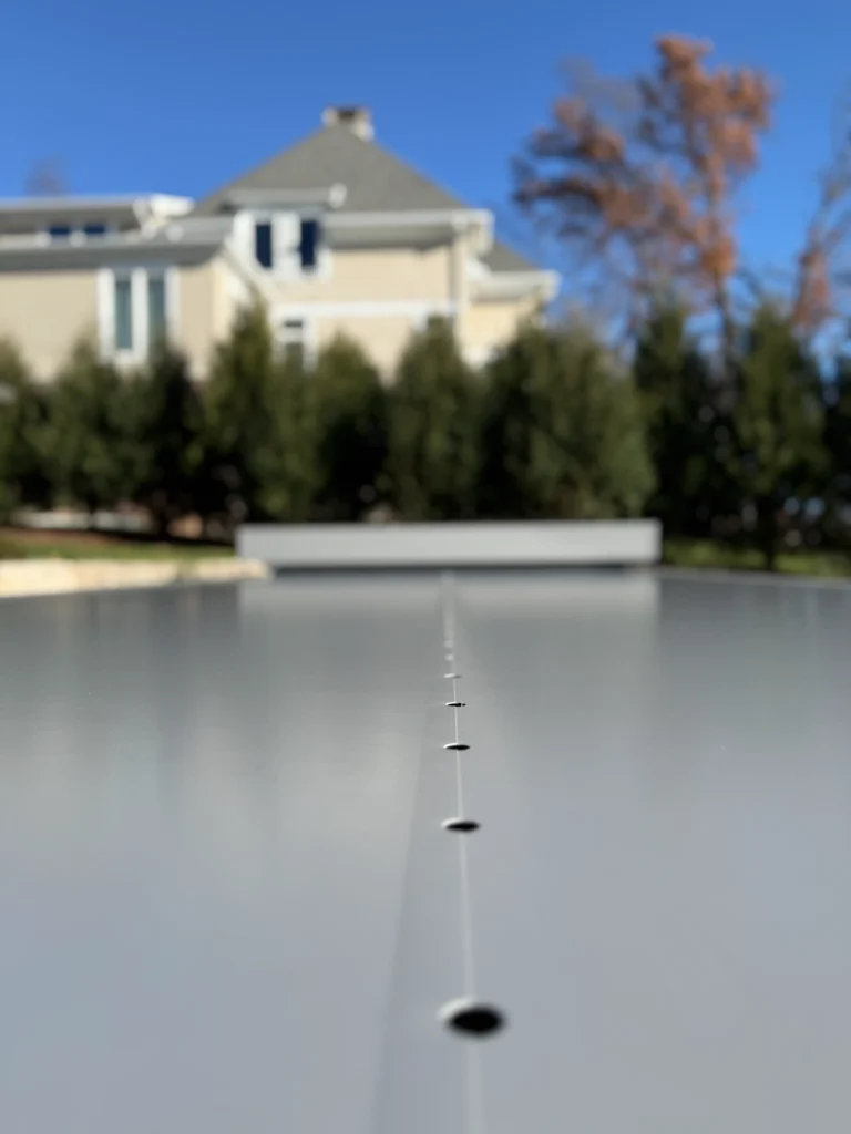 Coverseal automatic safety pool cover closed over an elegant backyard pool beside a spa cover, with mature trees and blue sky