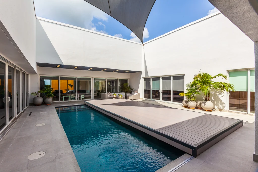 S-LIDE sliding deck pool cover integrated as a shaded outdoor patio next to a modern home, extending usable living space