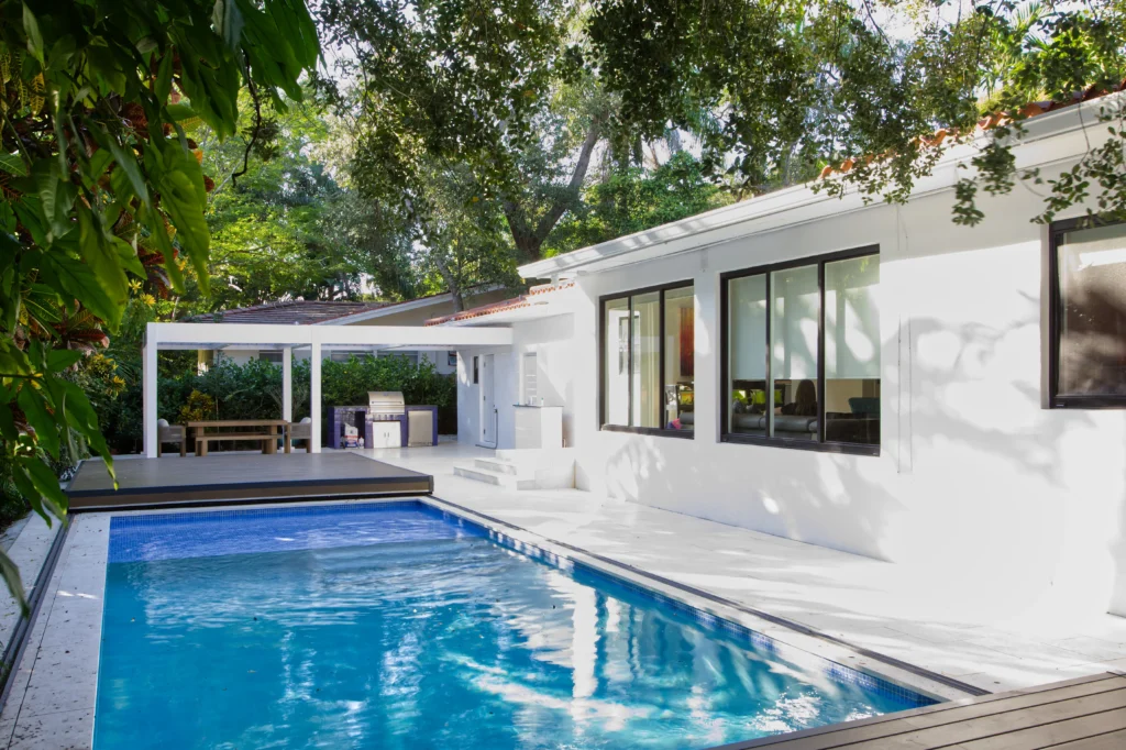 S-LIDE sliding deck pool cover partially open beside a modern home, revealing the pool and usable patio deck space