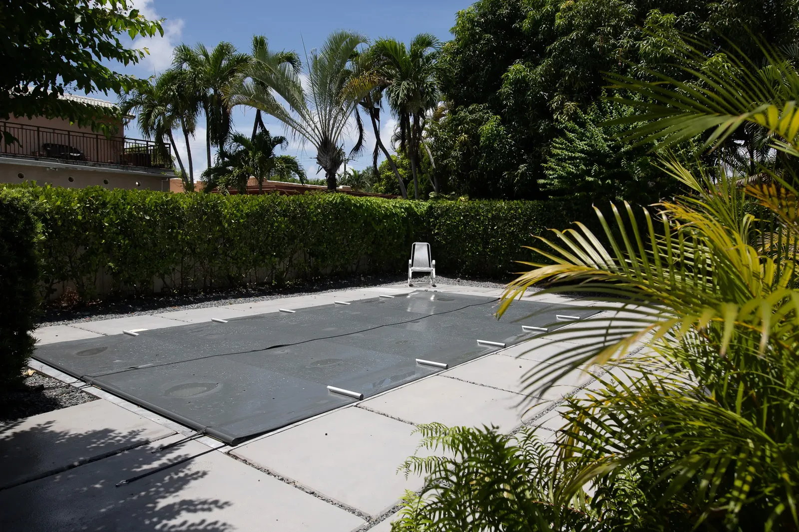 B-COVER manual trackless safety cover closed over a pool in a tropical Miami backyard
