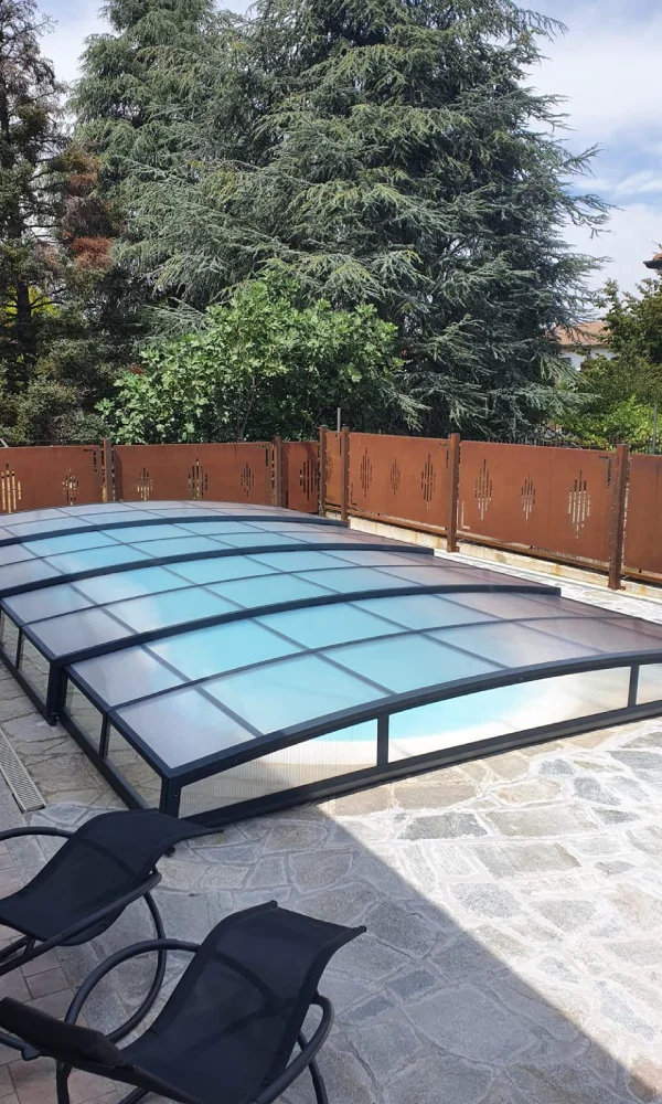 Retractable pool enclosure integrated into a contemporary outdoor pool design for weather and debris protection